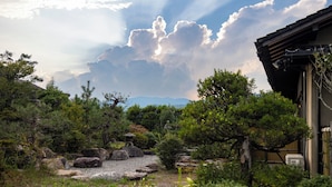 Een traditionele Japanse tuin met een stenen lantaarn, rotsen en bomen.