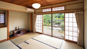 Een traditionele Japanse kamer met tatami vloerbedekking, schuifdeuren en uitzicht op een tuin.