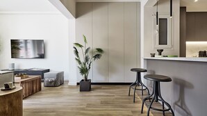 Une cuisine moderne avec un plancher en bois, une plante en pot et deux tabourets de bar.