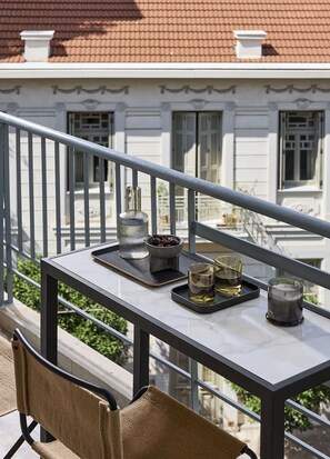 Un balcon avec une table préparée pour prendre un verre, une bougie et un vase décoratif.