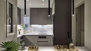 Une cuisine moderne dotée d’un îlot central, de luminaires suspendus et d’appareils électroménagers en acier inoxydable.