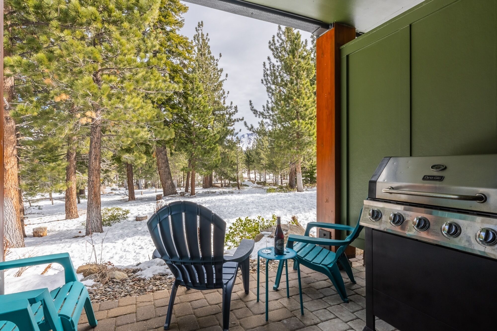 Un espace extérieur aménagé avec un barbecue, deux chaises et une table.