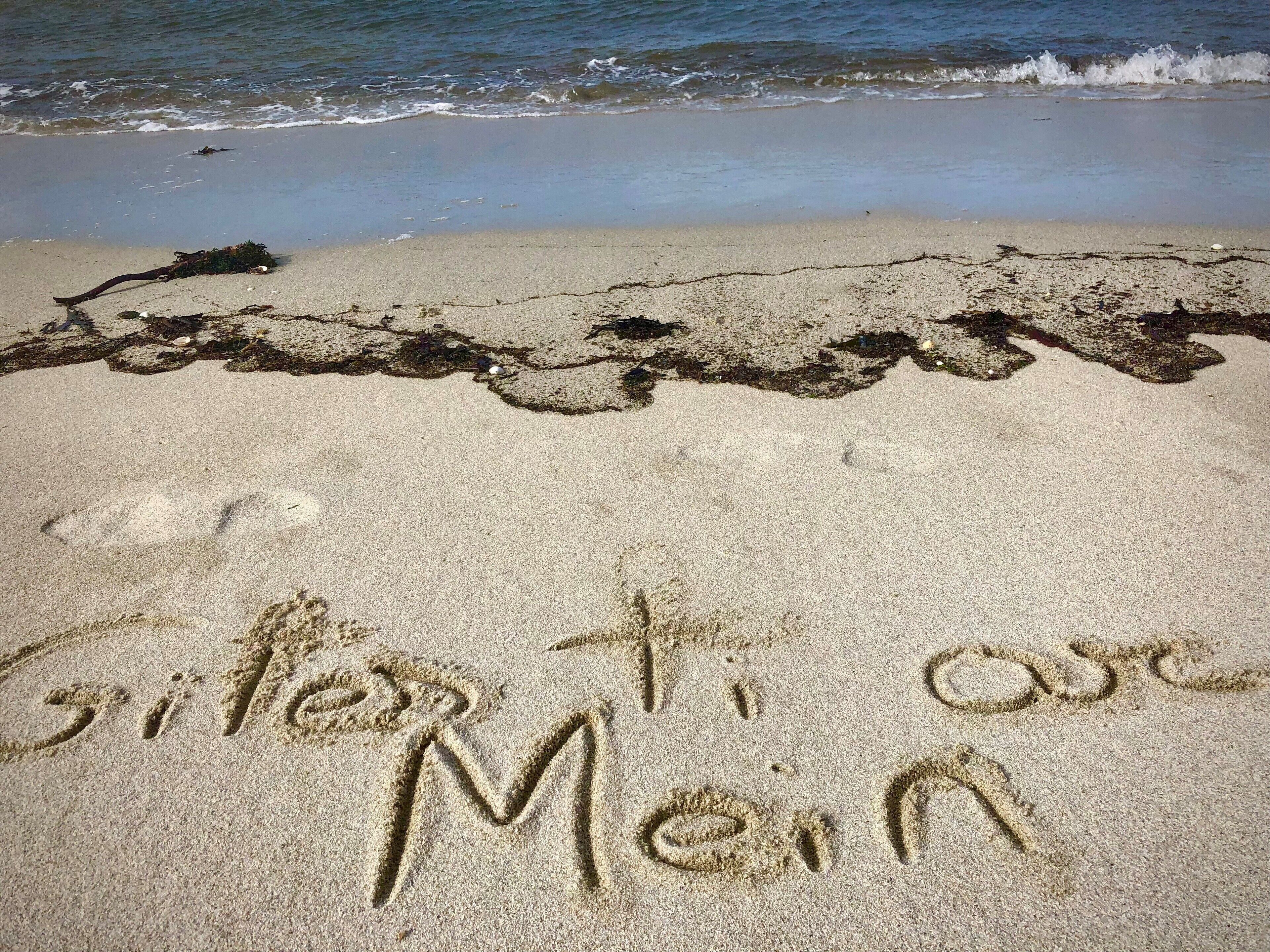 A beach with sand writing that reads "C'est toi avec Moi".