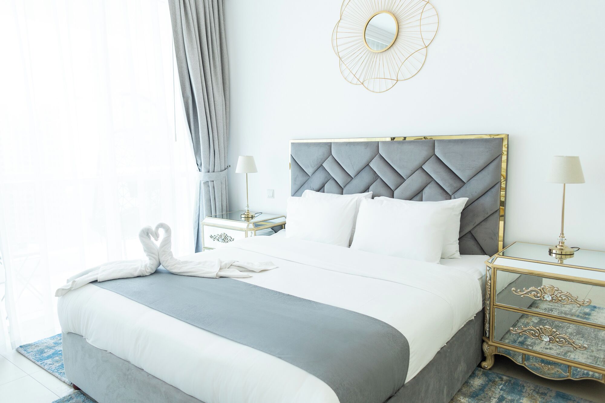 A hotel room with a large bed, a headboard, bedside tables, and a mirror.