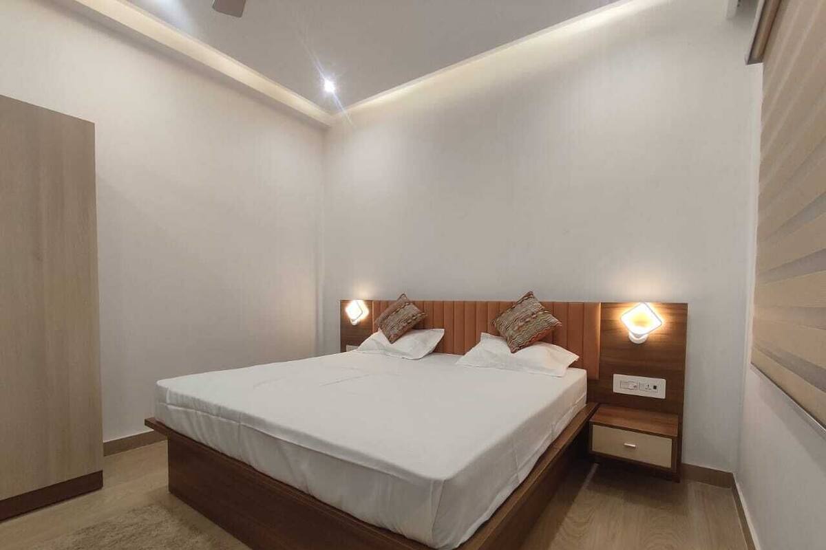 A modern bedroom with a wooden bed frame, two bedside tables with lamps, and a neutral color scheme.