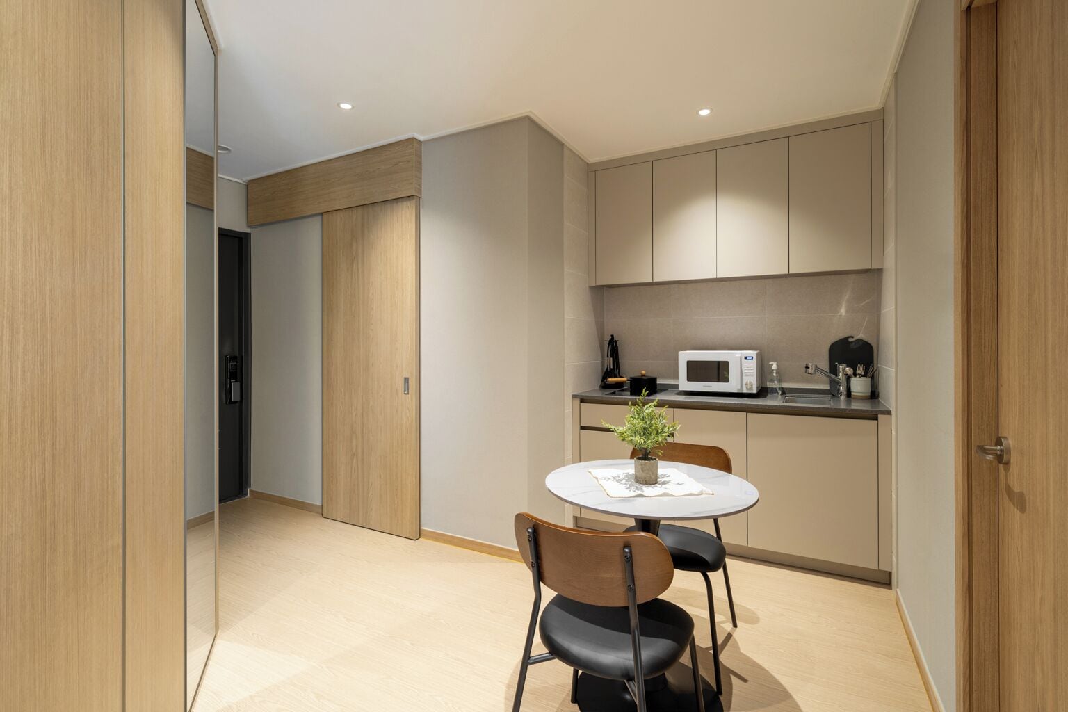 A modern kitchen with a microwave, a small sink, and a dining area with a table and chairs.