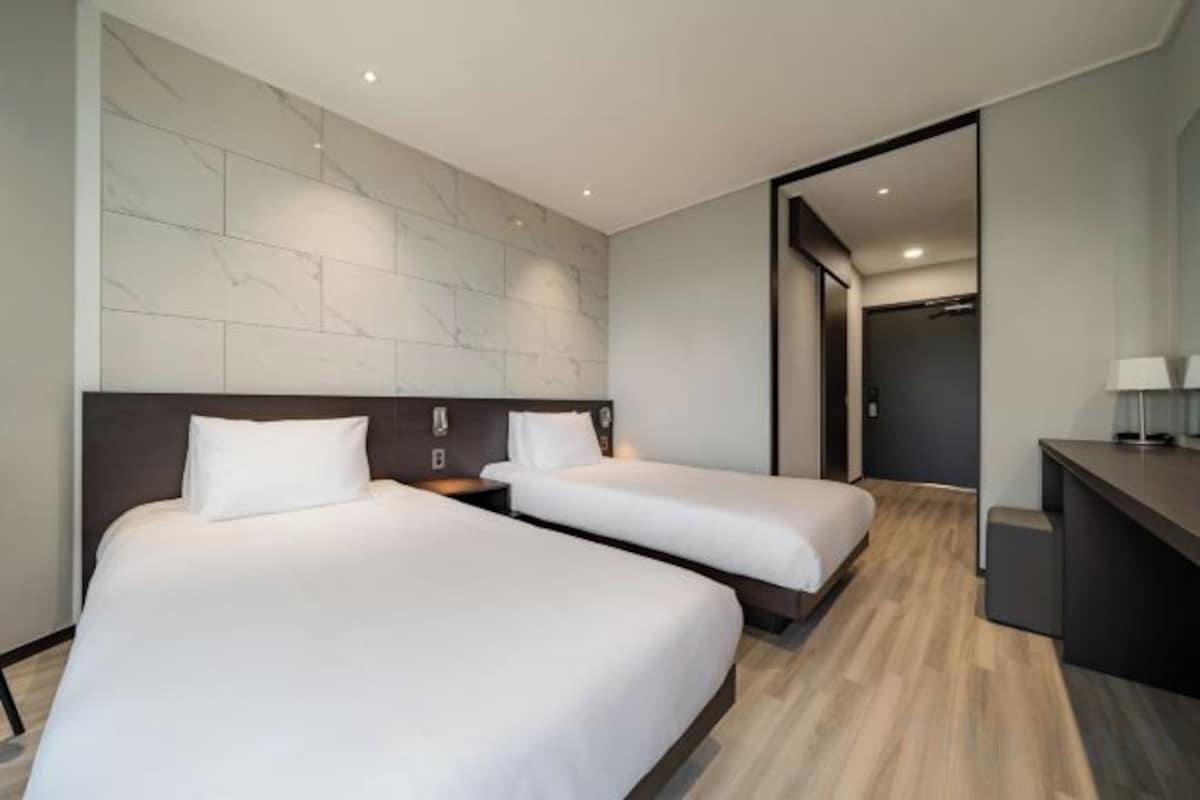 Habitación de hotel con dos camas, un escritorio y una pared de mármol.