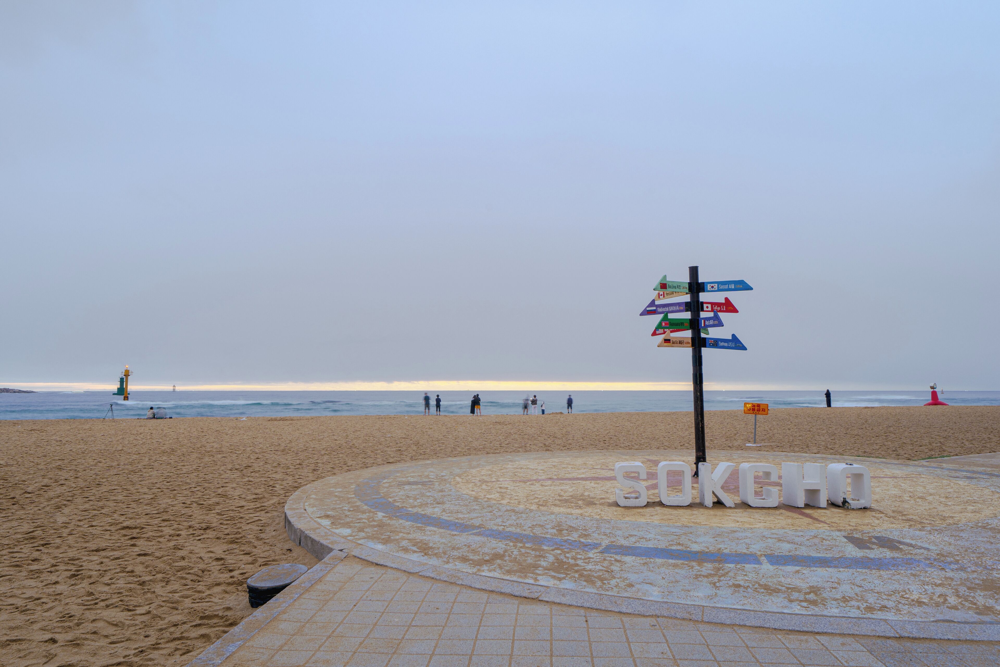 A beach with a signpost and the word "SOKCHO" on the ground.
