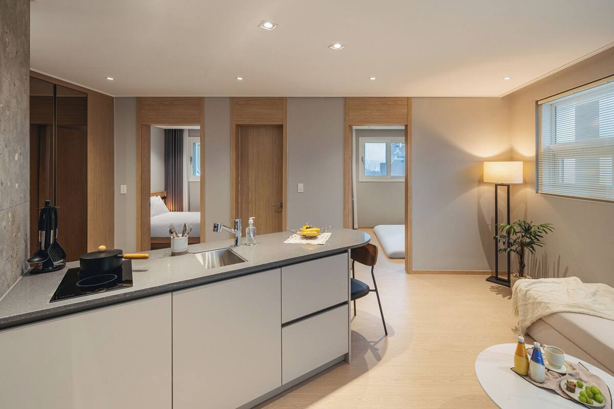 Eine moderne Küche mit einer zentralen Kochinsel, einem Essbereich mit einem Stuhl und einem Sofa.