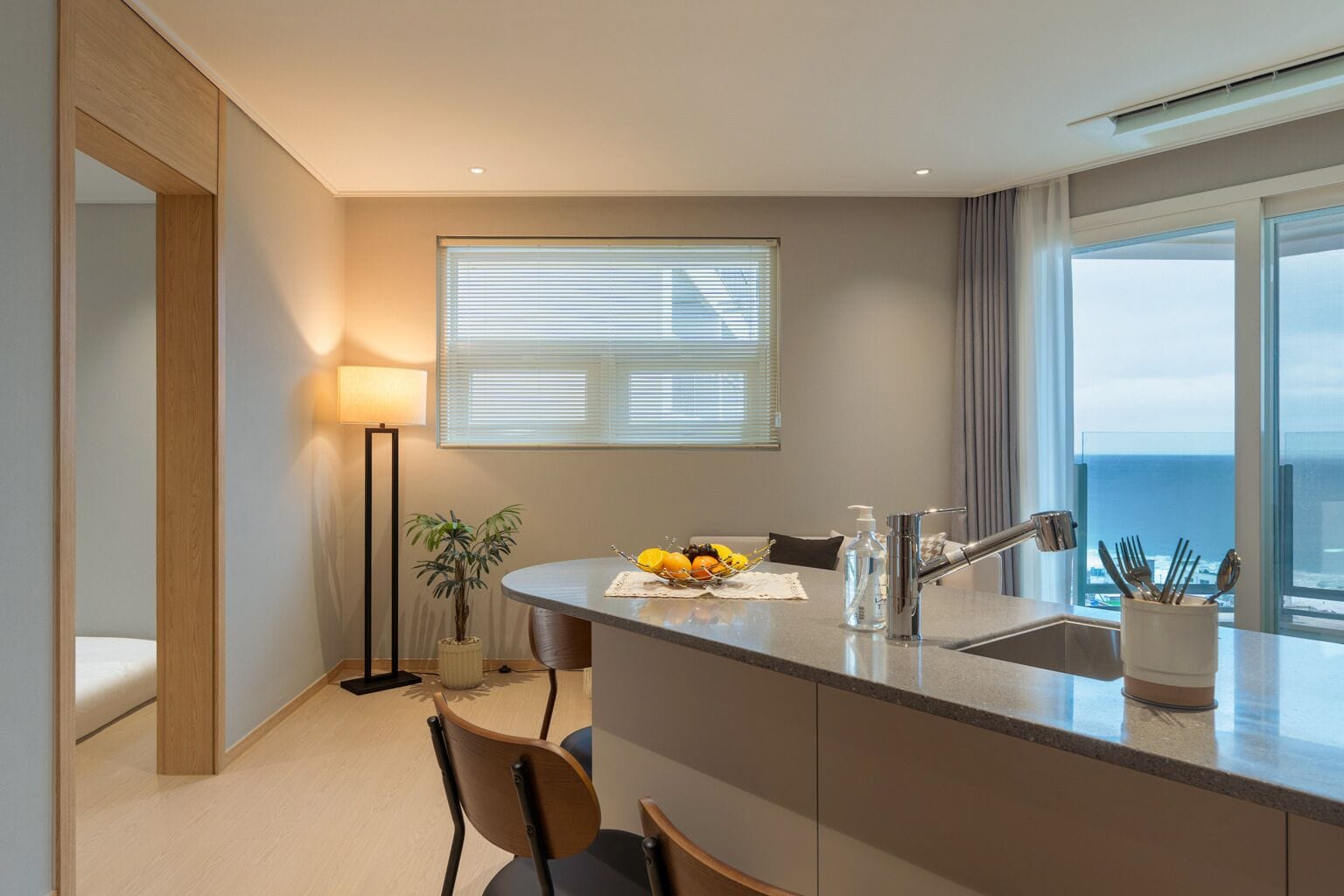 Una cocina moderna con una isla central, comedor y vistas al mar.