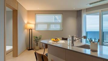 Una cocina moderna con una isla central, comedor y vistas al mar.