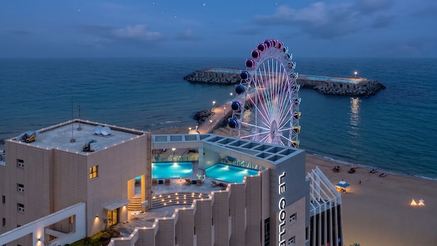 Un hôtel doté d’une piscine sur le toit, d’une grande roue et offrant une vue sur la plage.