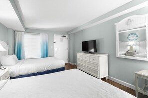 A bedroom with two beds, a TV, a dresser, and a mirror. - Beachside Bliss: Oceanfront Suite w/ Breakfast (Myrtle Beach)