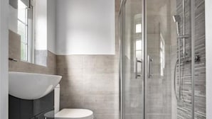 Et moderne badeværelse med et glasbadekar, en hvid vask og et toilet.