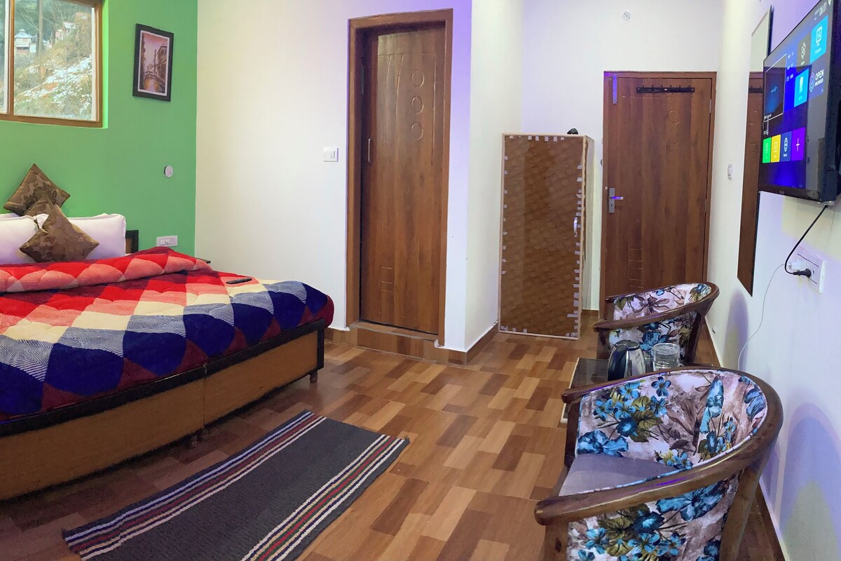 A bedroom with a bed, a chair, a TV, and a window with a view of trees.