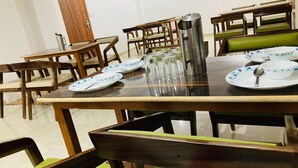 A dining area with a glass-top table, wooden chairs, and a metal pitcher.