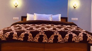 A hotel room with a bed, two wall-mounted light fixtures, a painting of the Eiffel Tower, and a power outlet on the wall.
