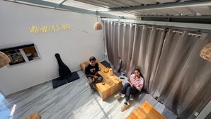 A modern living space with a sofa, a coffee table, and a small wooden table with drinks. - Odin Hostel Kasol (Bhuntar)