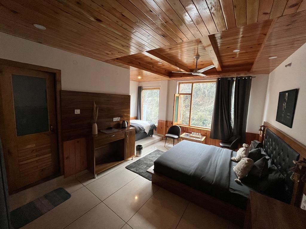 Een slaapkamer met een houten plafond, een bed, een bureau en een raam.