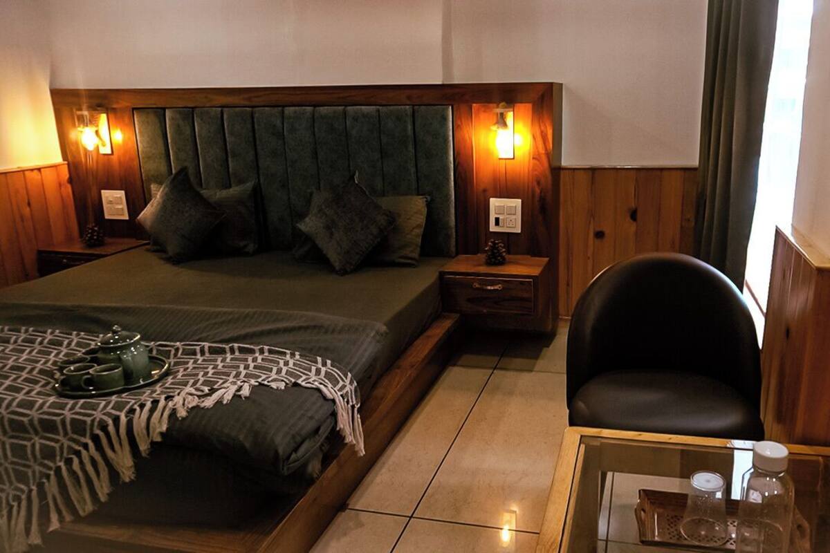 A hotel room with a bed, bedside tables, a chair, and a glass table with a tray.