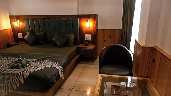 Una habitación de hotel con cama, mesitas de noche, una silla y una mesita de cristal con bandeja.