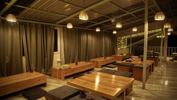 A modern interior with wooden furniture and hanging lights. - Odin Hostel Kasol (Bhuntar)