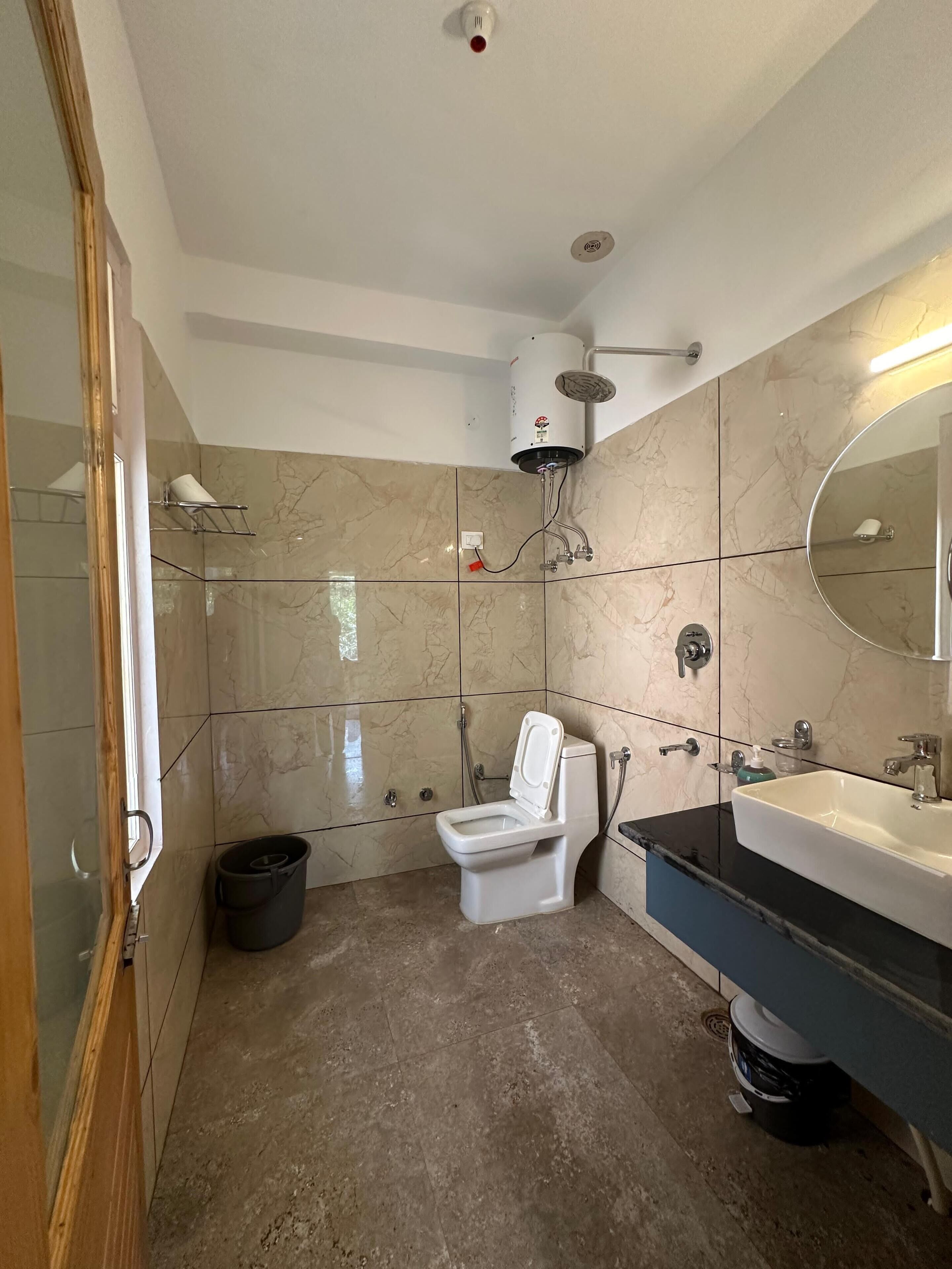 A bathroom with a toilet, sink, shower, and a mirror.