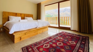 A double bed with a wooden headboard, a large window with curtains, and a view of mountains. - Askireg Hotel (Pülümür)