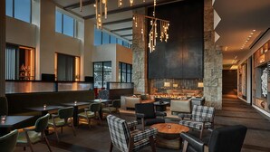 A spacious lobby with a fireplace, comfortable seating, and a bar area.
