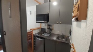 A compact kitchen with a microwave, stove, sink, and cabinets. - Studio 2/3 pers 20m from gondola, equipped kitchen, south balcony, pets allowed (Valfréjus)