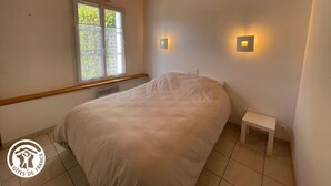 Une chambre à coucher avec un lit, une fenêtre et deux lampes fixées au mur.