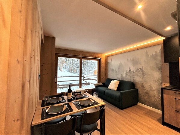A modern interior with a dining area, a sofa, and a view of a snowy landscape.