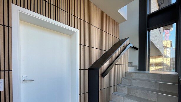 A modern interior with a staircase, a white door, and a wooden panel wall.