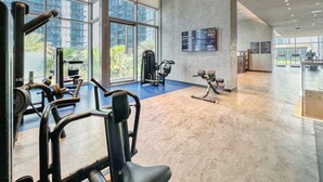 Uma academia ampla com diversos equipamentos de exercício, janelas grandes e design moderno.