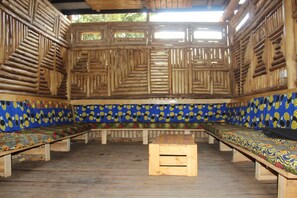 Une pièce avec un long banc le long d’un des murs, une petite table en bois au centre et un mur orné d’un motif.