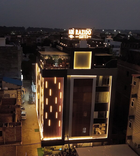 A hotel with a sign reading "MAAN HOTEL ROOMS" and "RAZIDO SUITES".