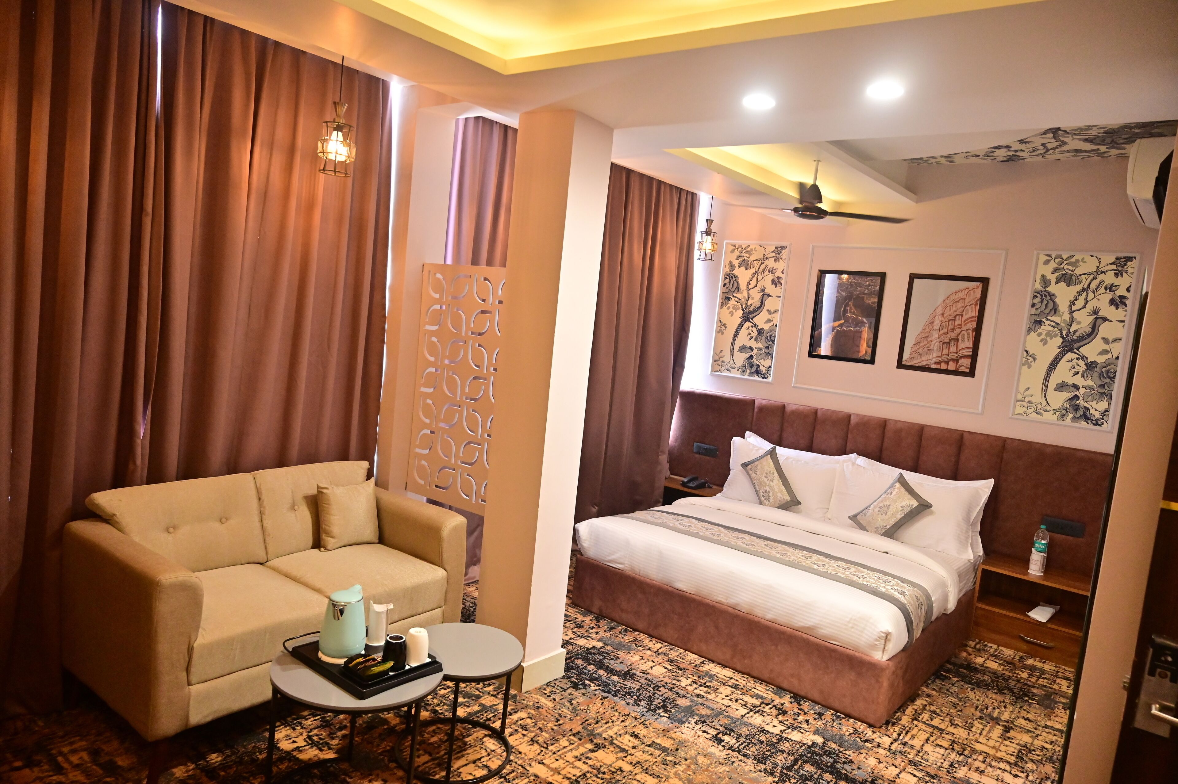 Una habitación de hotel con una cama, un sofá, una mesita y un panel decorativo en la pared.