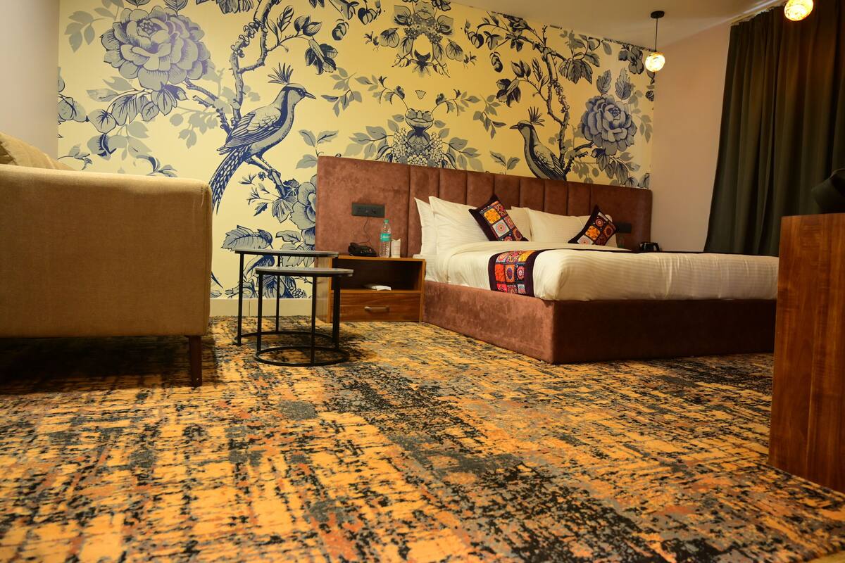 A hotel room with a bed, a sofa, a small table, and a nightstand.