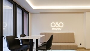 A modern interior with a sofa, chairs, a table, and a wall with 'OSO MADRID' illuminated signage.