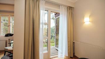 Habitación con puerta de vidrio corrediza que da a un espacio exterior, una mesita con una silla y una lámpara fijada a la pared.