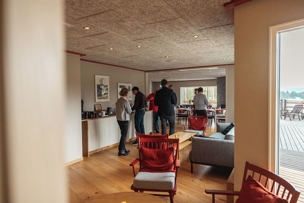 Una habitación amplia con suelo de madera, una zona de cocina y un espacio de estar con sillas rojas y un sofá gris.