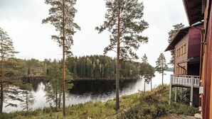 Una cabaña con terraza que da a un lago rodeado de árboles.