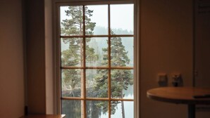 Habitación con un ventanal grande que ofrece vistas a un bosque y una masa de agua.