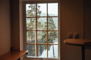 Habitación con un ventanal grande que ofrece vistas a un bosque y una masa de agua.