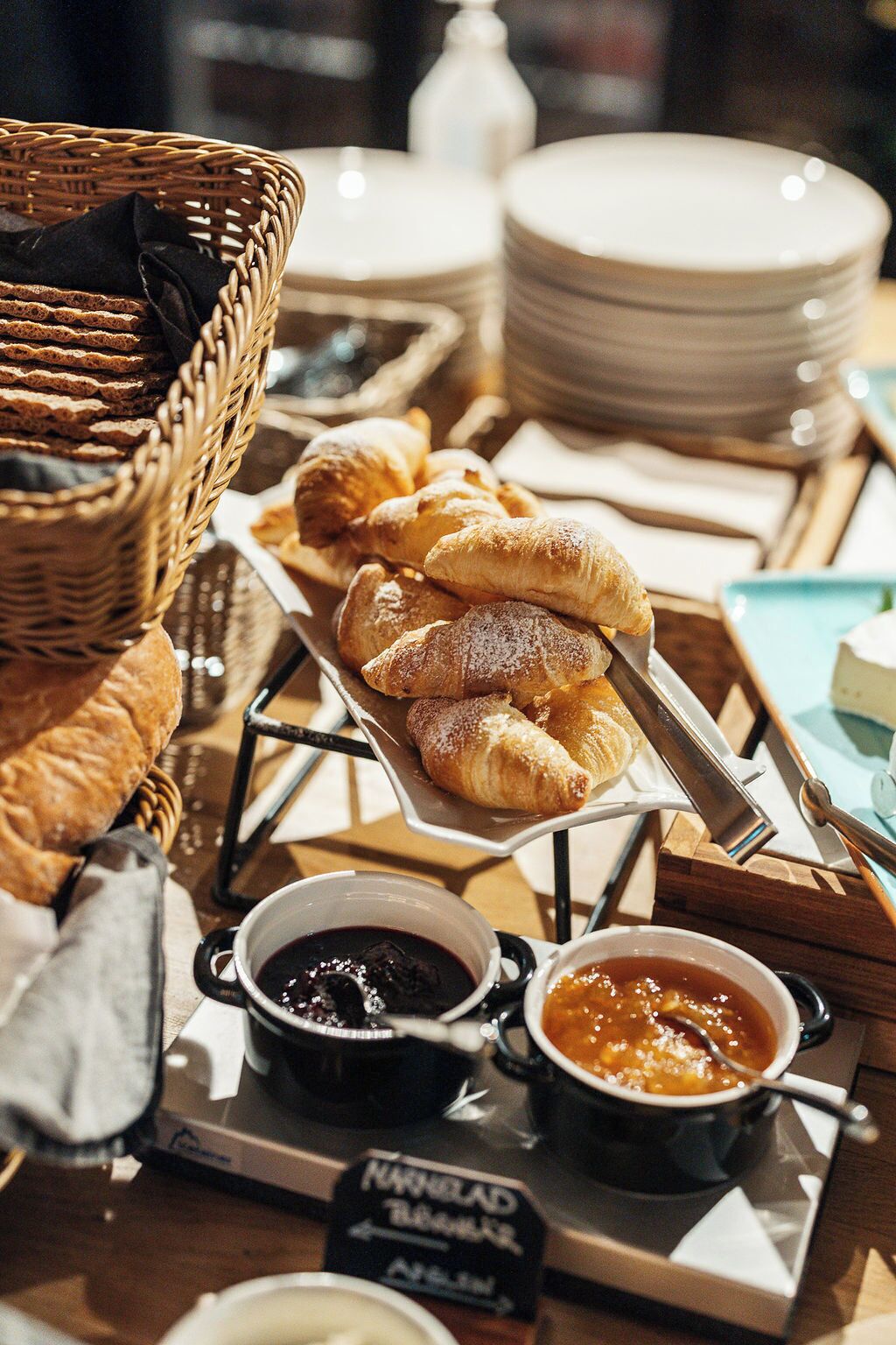 Un buffet de petit-déjeuner proposant des viennoiseries, des confitures et une pancarte indiquant : « Petit-déjeuner à la sauce assistancialiste ».