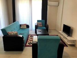 Una sala de estar con sofá, sillón, mesa de centro, televisor y alfombra.