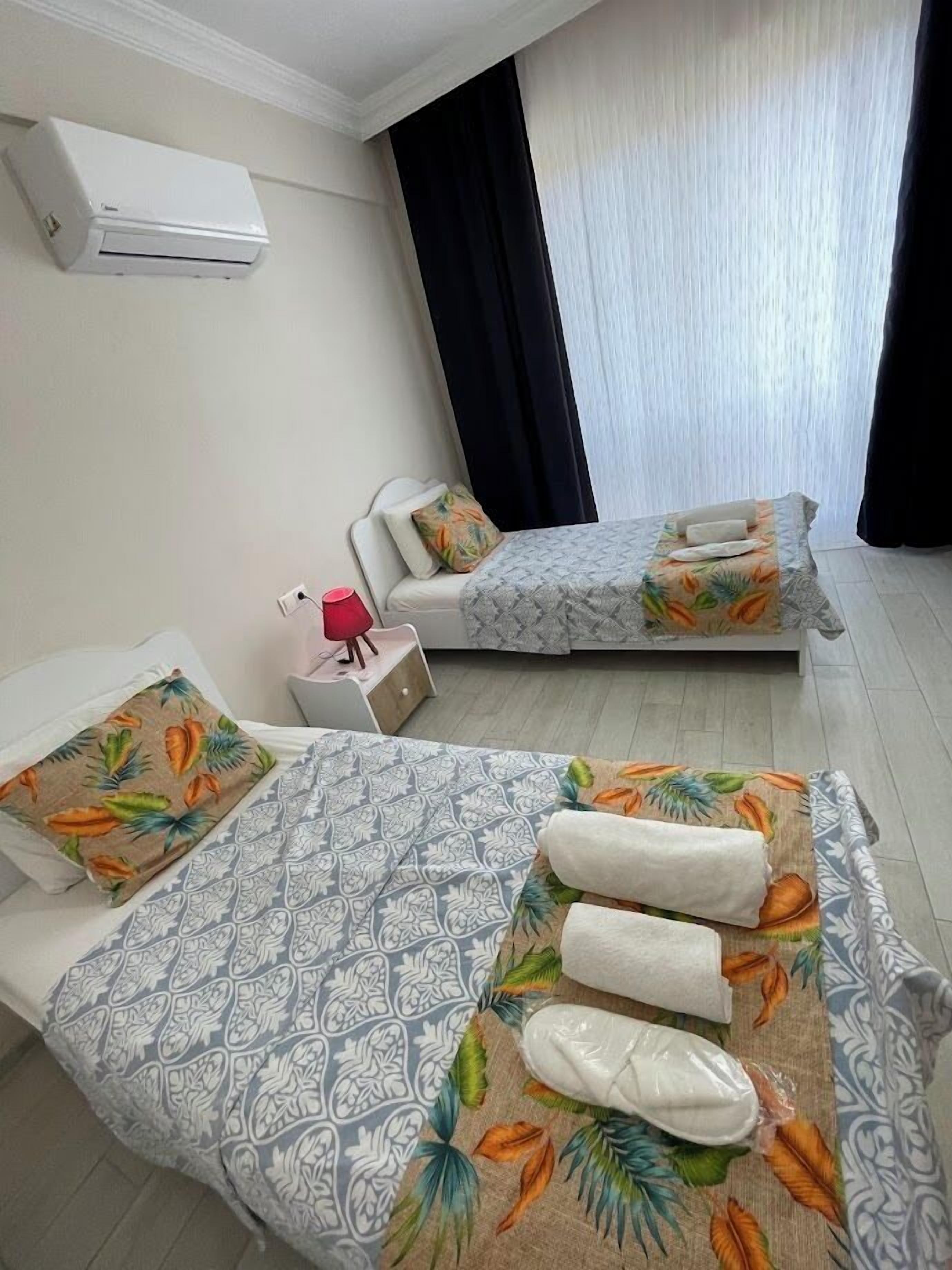 Une chambre d’hôtel avec deux lits, une table de chevet, une lampe et un appareil de climatisation.
