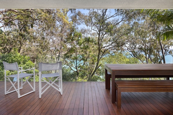 A wooden deck with a white metal chair and a wooden table.