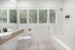 Ein modernes Badezimmer mit Toilette, Waschbecken und Badewanne.