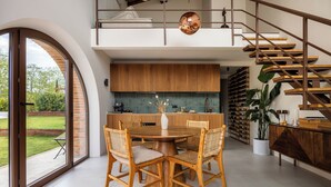 A modern kitchen with a dining area, a staircase, and a view of the outdoors.